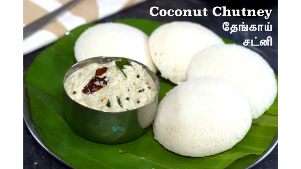 A plate of steamed idlis served with creamy coconut chutney and spicy sambar.