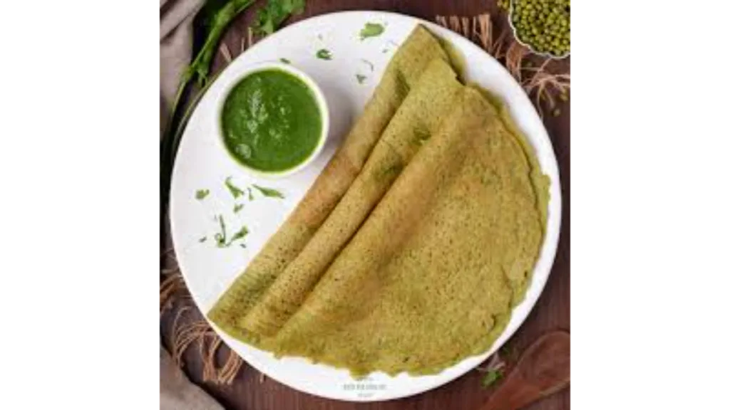Crispy moong dal chilla stacked on a plate, paired with green chutney.