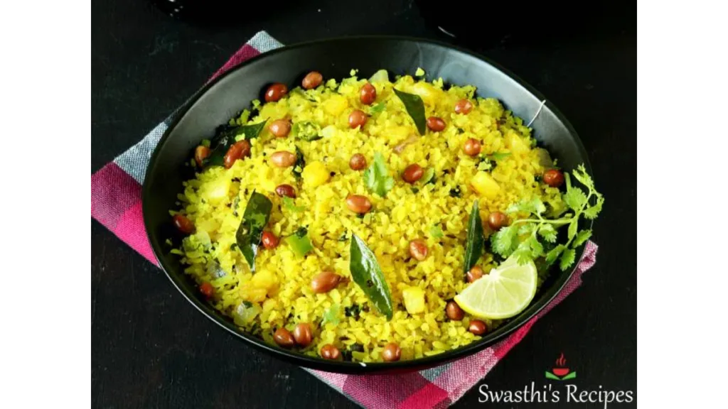 A plate of freshly made poha garnished with peanuts, curry leaves, and lemon; a classic healthy Indian breakfast choice.