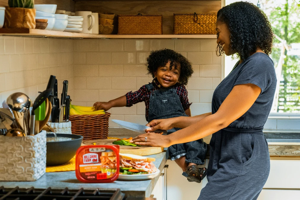 Parent and child smiling while preparing a meal together, reinforcing kitchen safety for kids.