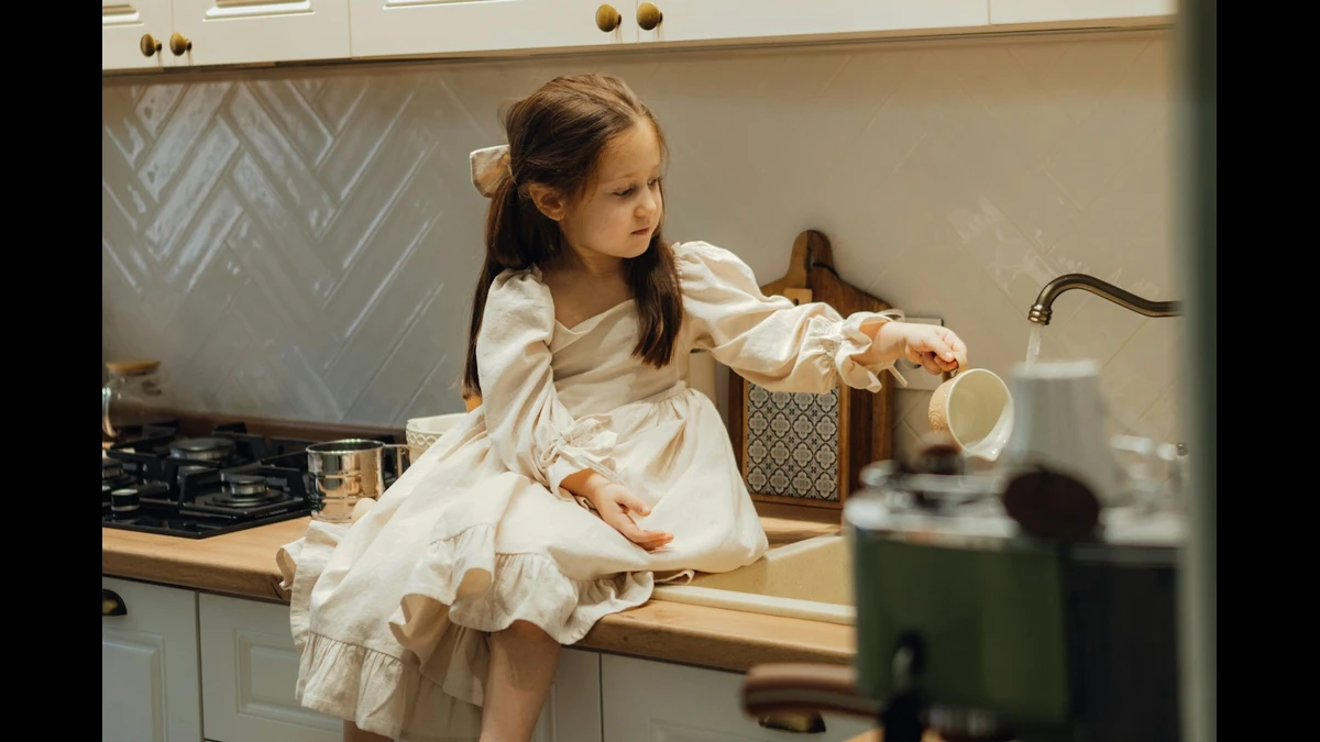 A child using a safe step stool to reach the kitchen counter, practicing kitchen safety for kids.